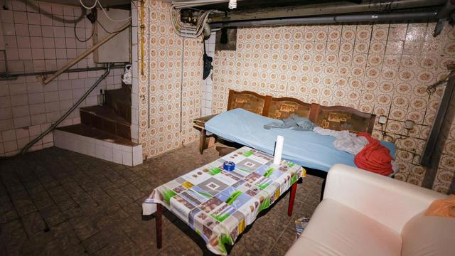 Kellerraum einer "Schrottimmobilie" mit mehreren provisorischen Schlafplätzen und einem Holztisch