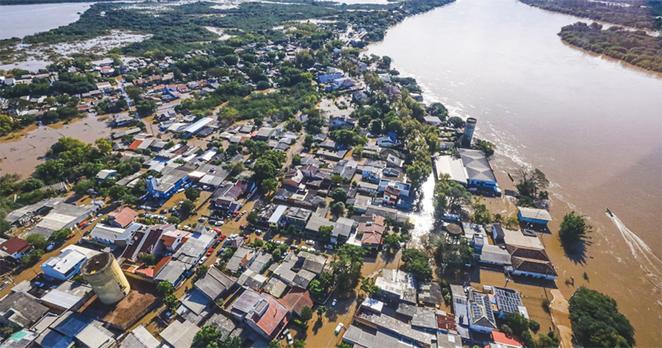 vista aérea de área residencial às margens de rio atingida por inundações, com as águas ocupando o leito das ruas por entre as casas, que se concentram na parte inferior da imagem, enquanto na superior aparecem áreas verdes tomadas pelas águas vista aérea de área residencial às margens de rio atingida por inundações, com as águas ocupando o leito das ruas por entre as casas, que se concentram na parte inferior da imagem, enquanto na superior aparecem áreas verdes tomadas pelas águas