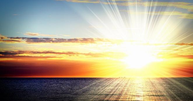 Sonnuntergang über dem Meer. Die Sonne sendet einen hellen Strahlenkranz, der an die Zeiger einer Uhr erinnert. Sonnuntergang über dem Meer. Die Sonne sendet einen hellen Strahlenkranz, der an die Zeiger einer Uhr erinnert.