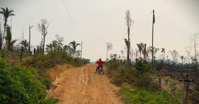 A man rides a motorcycle down a dirt road