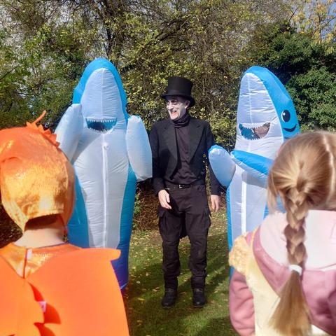 Two volunteers in inflated shark costumes dancing with museum director Mike Pringle, who is dressed in a top hat and tail, with ghoulish face paint. Two volunteers in inflated shark costumes dancing with museum director Mike Pringle, who is dressed in a top hat and tail, with ghoulish face paint.