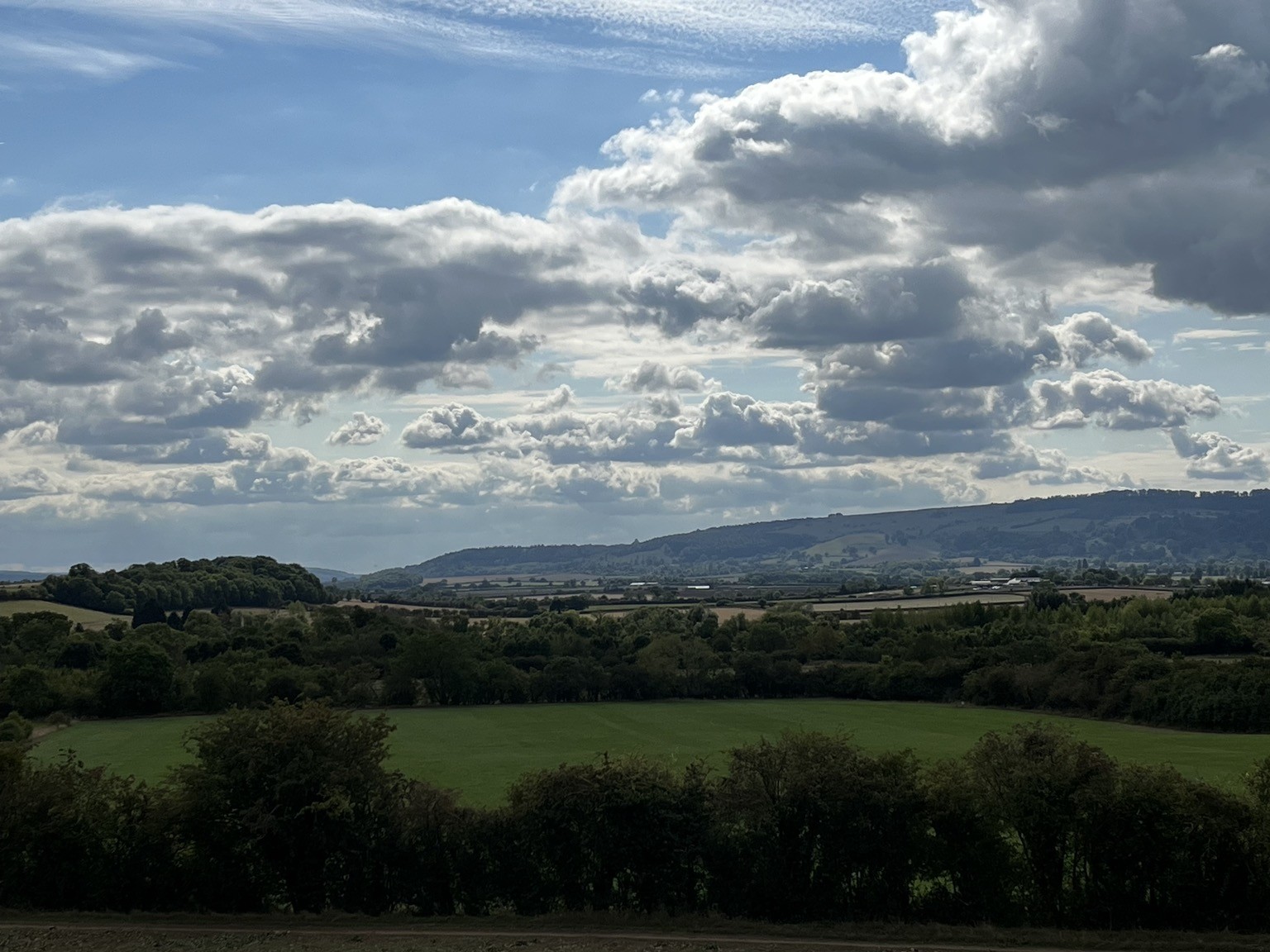 Clouds and sunlight play on the Cotswold Hills, seen from the Evesham Vale
