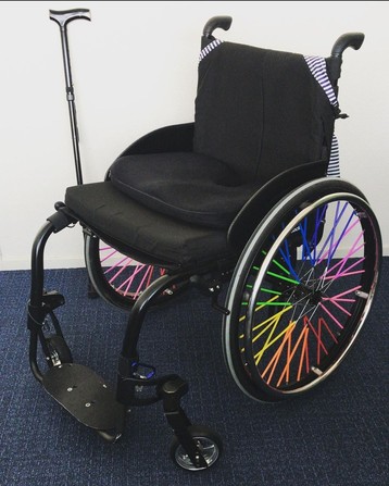 My old Ottobock ventus standing near a white wall on a dark blue floor, showing its rainbow wheels