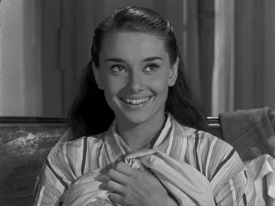 Audrey Hepburn in Roman Holiday. She is wearing men's pajamas and puling the sheets up to her chest. She's smiling and looking up. This is just about the most adorable image on the planet. 