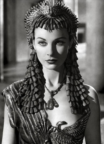 Vivien Leigh in a costume for Cleopatra with an elaborate headdress and a low cut robe type thing. Her expression is either blank or cutting. 