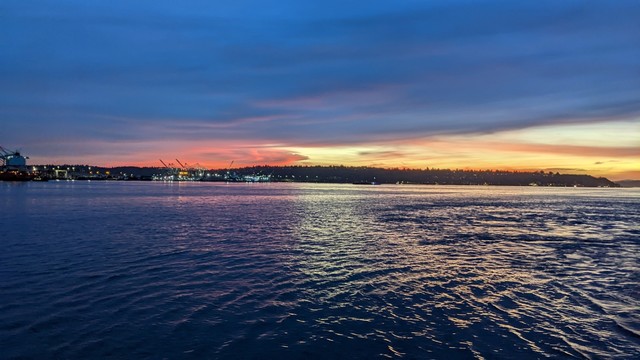 The sun sets behind South Seattle, reflecting off the waters of Puget Sound