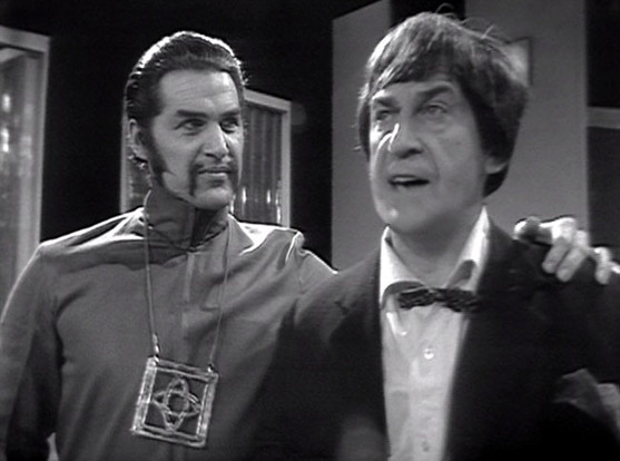 Edward Brayshaw as The War Chief in Doctor Who - The War Games, with slicked back hair and a handlebar moustache, with his arm round Patrick Troughton as the Doctor