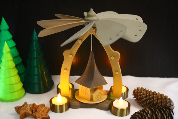 3D Printed Christmas Pyramid with LED tea lights. In the background are 3D printed Christmas trees.
