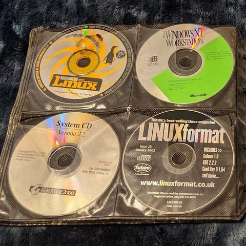 A second page from a Case Logic CD/DVD holder with 4 vintage software CDs.  The CDs are Maximum Linux, Windows NT Workstation 3.5, a Gateway 2000 OEM software CD, and LINUXformat issue 23 from January 2002.
