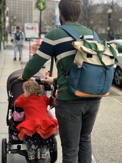 A father pushes a stroller with an infant and a toddler seated on it
