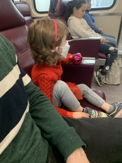 A masked toddler sitting on the MBTA commuter rail