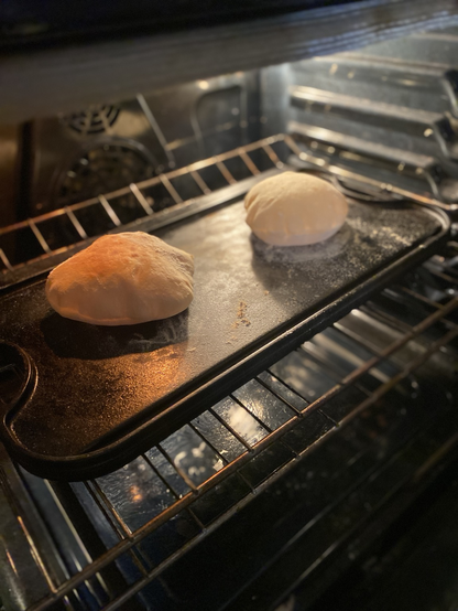 Two loaves of pita puffing in the oven