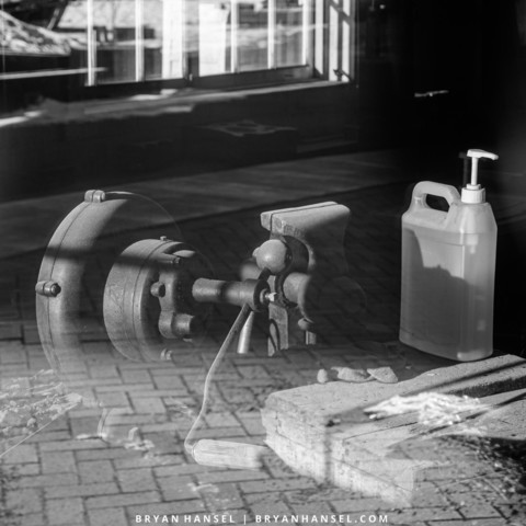 A black and white infrared image of reflections in a window: metal grinder and hand sanitizer.