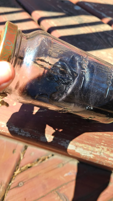 The same jar tipped slightly sideways so that the dark liquid can be seen.