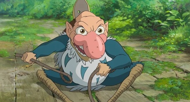 The blue heron with his big red nose is grinning, sitting down on the ground and holding rope.