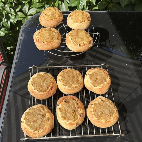 All ten onion breads resting on two cooling racks on my outside table. The crust is a beautiful golden and the onion topping (or filling) is nicely caramelised. I baked the breads at 230°C/446°F, for fifteen minutes.pic 