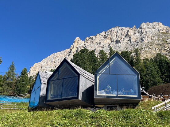 View on the Oberholz Hütte from outside. The facade consists of three 'house shaped' large windows, through which the inside is visible.