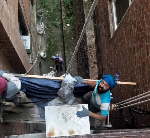 View down on workers on hanging scaffolding rig,
 stories above ground