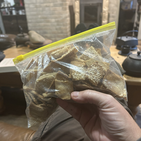Closeup of a freezer bag filled with my newly baked sesame crackers. It's not an elegant look, as containers go, but they are properly airtight and take up little space. 