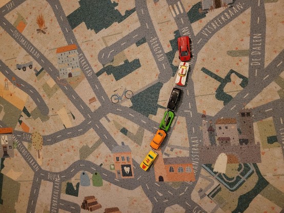 A row of toy cars on a playmat with a map on it.