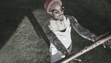 Andre 3000 cradles a wooden flute in an image from 2023.
