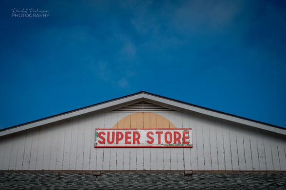 Upper portion of storefront with "SUPER STORE" painted in red letters on a white background. 
