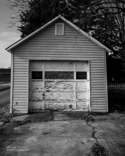 Single car garage with weathered white door. 