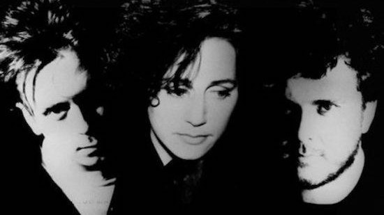 Three members of the Cocteau Twins pose in a moody black and white photograph. 