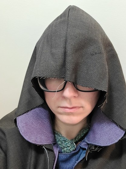 A woman wearing a brown fabric hood that flops down over her eyes