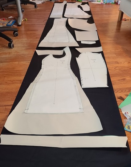 Paper pattern pieces laid out on a length of dark fabric.  All of them show evidence of a variety of modifications.