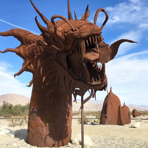 My iPhone photo of Ricardo Brecedo dragon in Galleta Meadows; it’s huge & scary & awesome & rusty, it’s installed in sandy desert ground & the sky is bright blue behind it with wispy white clouds