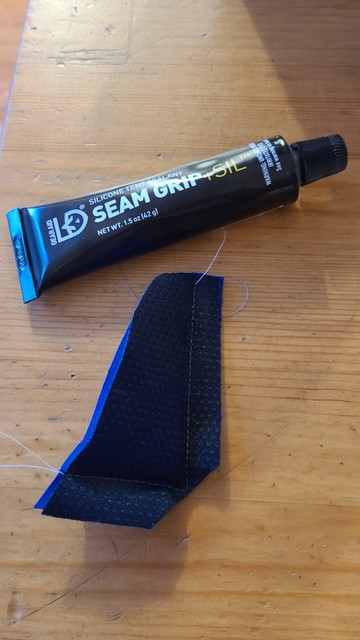 A tube of silicone seam grip and a pair of triangular scraps sewn together on two sides.