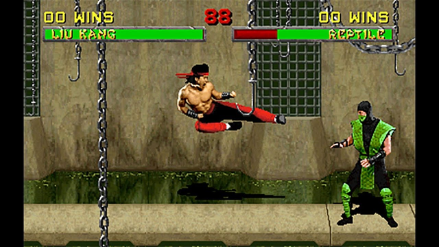 Video game still of Liu Kang performing a flying kick in Mortal Kombat. He is shirtless, with black and red pants and is yelling as he flies five feet off the ground towards Reptile.