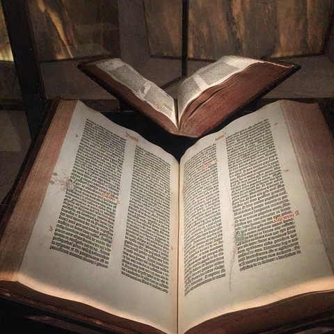 Two large open books with Latin text, the Gutenberg Bible, on display in a glass case at the Yale Beinecke Rare Book & Manuscript Library.