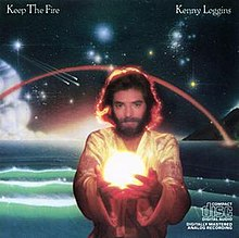 From the wikipedia entry, "Kenny Loggins, a long-haired bearded man, holding football-sized glowing sphere, standing in front of fantastic space scene above an ocean."