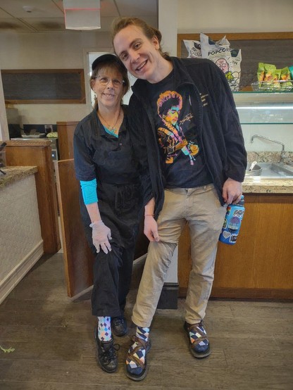 A woman and a man standing together lifting their pants slightly to show off argyle socks.