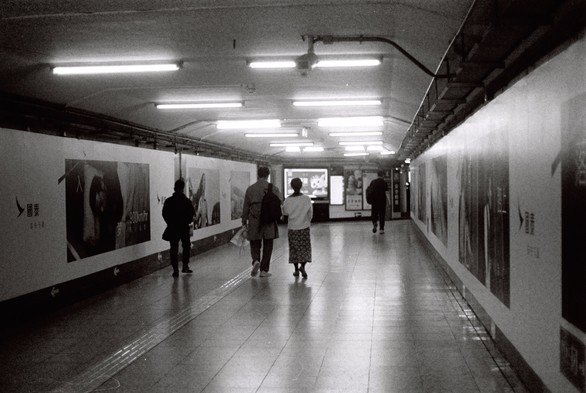 A black and white picture of people walking in a tunnel.