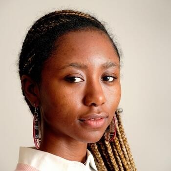 A close up of a Black woman in a white collar shirt and long, oval earrings.