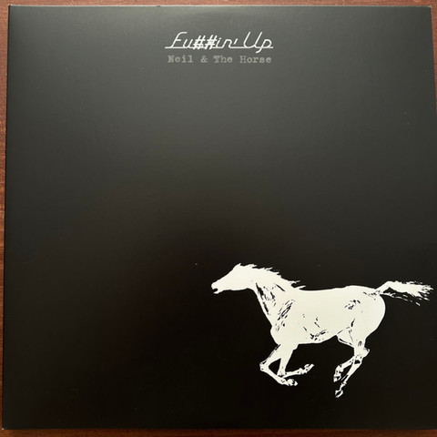 A white silhouetted horse charges across a black background on Neil Young and Crazy Horse's live album Fuckin' Up from 2024. 