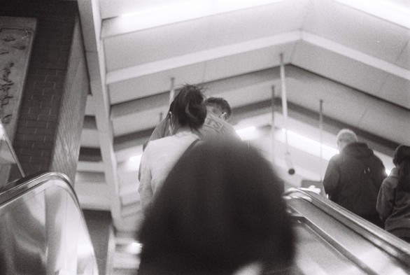 A black and white picture of people ascending on an escalator