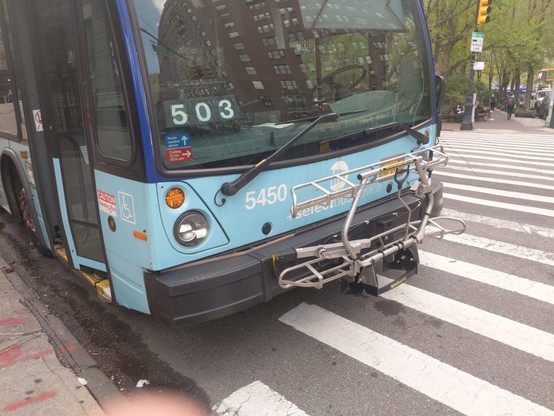 SBS M60 bus waiting at 106th next to Strauss Park with a bicycle rack.