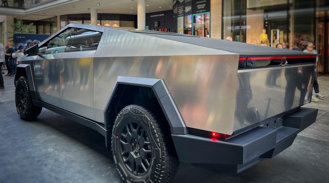 Der Cybertruck, das sehr eckige, silberne E-Auto von Tesla, steht in einem Einkaufszentrum herum und wird von Menschen besichtigt.