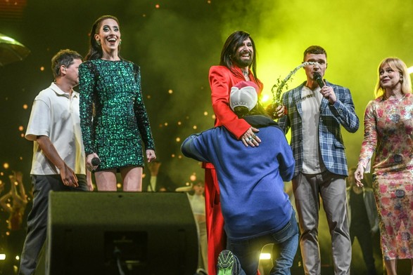 meelis kneeling and gently hugging conchita holding a flower