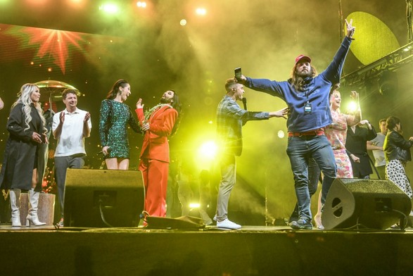 meelis showing a victory sign on stage, conchita and others emotional in background
