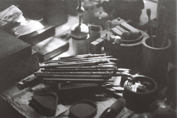 A black and white image of traditional Chinese stationary: The ink stone, the brush, the rice paper and the ink.