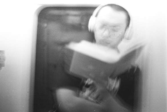A black and white image of a blurry image of a man reading in the train