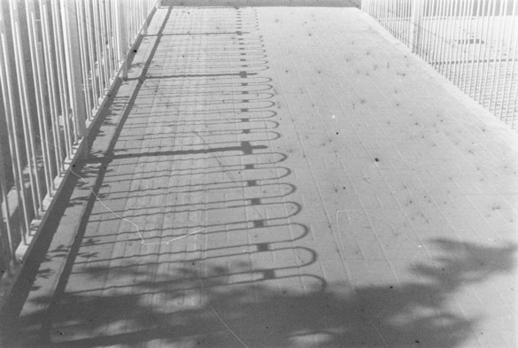 A black and white image of Fences and their shadows on the street