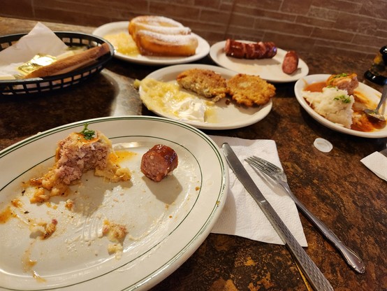 A spread of polish food including sausage, potato pancakes. Stuffed cabbage. Cheese blintz.