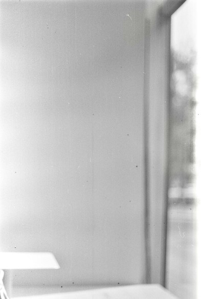 A black and white image of half a table standing by the side of a window.