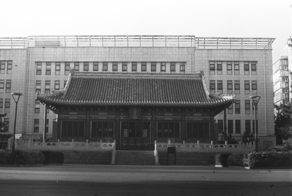 A black and white image of a temple standing in front of a modern building